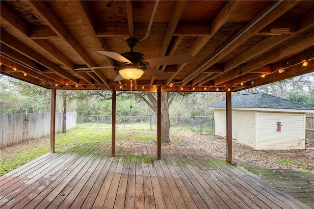 deck with a storage shed, an outdoor structure, a fenced backyard, and a ceiling fan