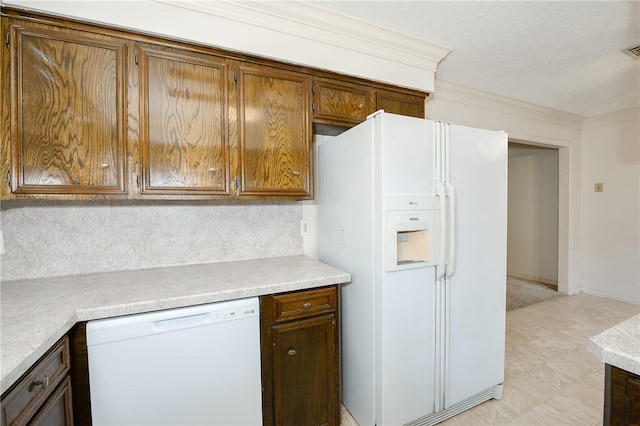 kitchen with brown cabinets, crown molding, light countertops, visible vents, and white appliances