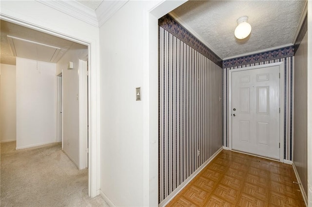 hall featuring attic access, crown molding, a textured ceiling, and baseboards