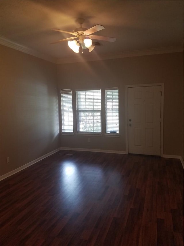 spare room featuring baseboards, ceiling fan, crown molding, and dark wood-type flooring
