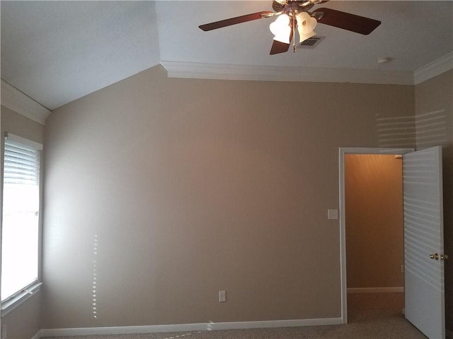 carpeted spare room featuring crown molding, ceiling fan, visible vents, baseboards, and vaulted ceiling