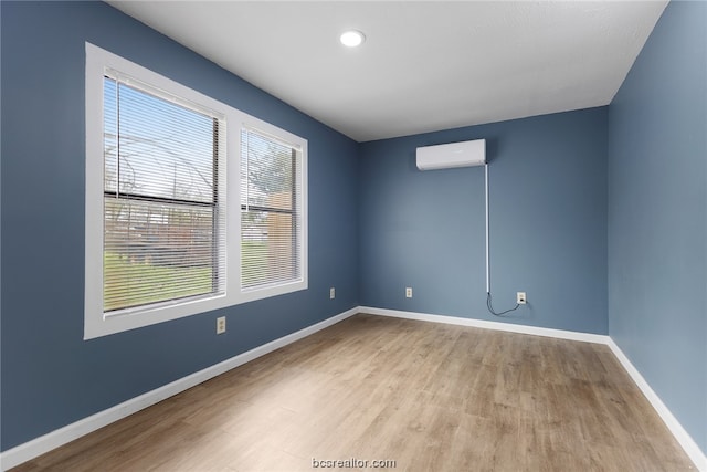 empty room featuring an AC wall unit and light hardwood / wood-style flooring