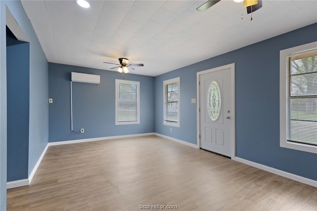 entryway with an AC wall unit, a wealth of natural light, ceiling fan, and light wood-type flooring