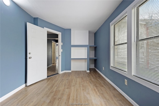 unfurnished bedroom with multiple windows, a closet, and light hardwood / wood-style floors