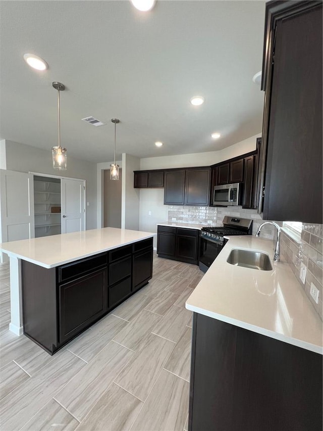 kitchen with sink, tasteful backsplash, a center island, appliances with stainless steel finishes, and pendant lighting