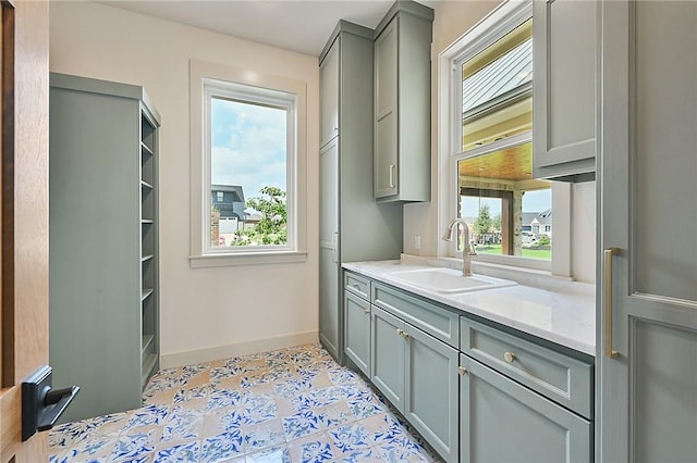 interior space with gray cabinets, sink, and light tile patterned flooring