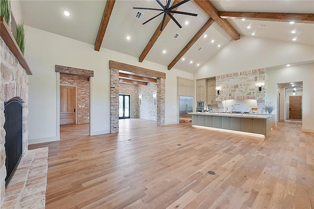 unfurnished living room featuring beamed ceiling, light wood-type flooring, high vaulted ceiling, and ceiling fan