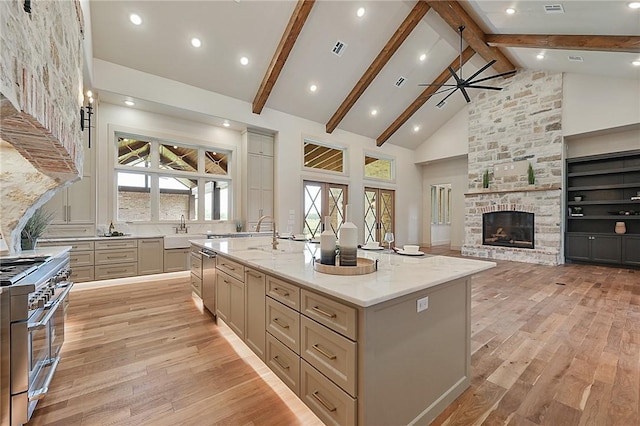 kitchen featuring a large island, stainless steel appliances, light stone counters, high vaulted ceiling, and plenty of natural light