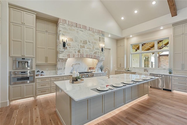 kitchen featuring stainless steel dishwasher, a kitchen island with sink, and light hardwood / wood-style flooring