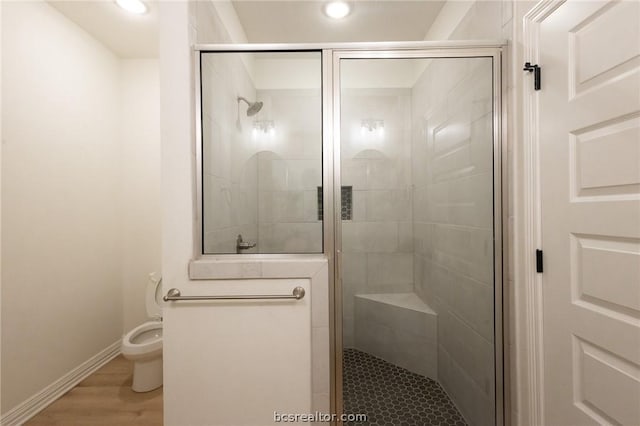 bathroom featuring hardwood / wood-style floors, toilet, and a shower with door