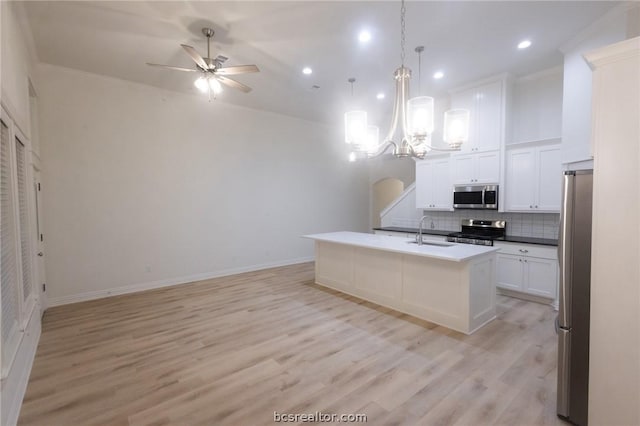 kitchen with appliances with stainless steel finishes, sink, decorative light fixtures, a center island with sink, and white cabinets