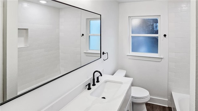 full bathroom with hardwood / wood-style flooring, tiled shower / bath, vanity, and toilet