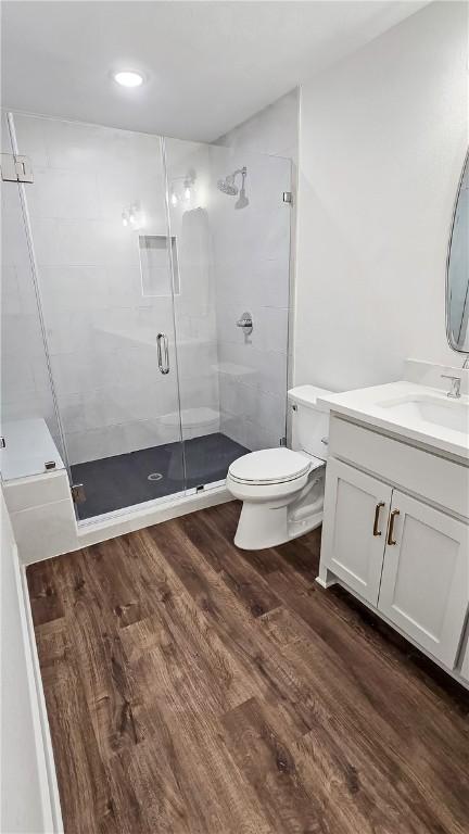 bathroom featuring vanity, hardwood / wood-style flooring, a shower with door, and toilet