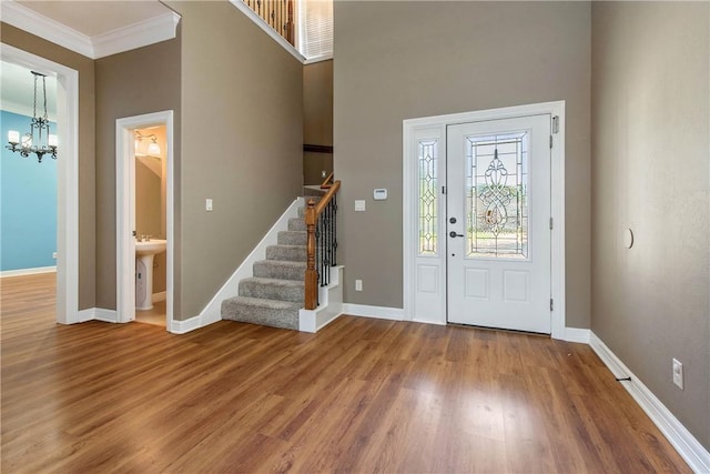 foyer featuring crown molding, an inviting chandelier, a high ceiling, and hardwood / wood-style flooring