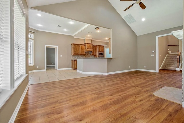 unfurnished living room with crown molding, light hardwood / wood-style flooring, high vaulted ceiling, and ceiling fan