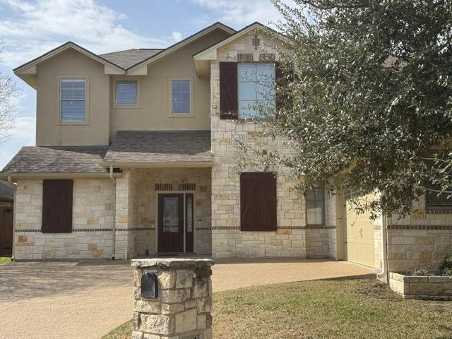 view of front facade featuring stone siding and roof with shingles