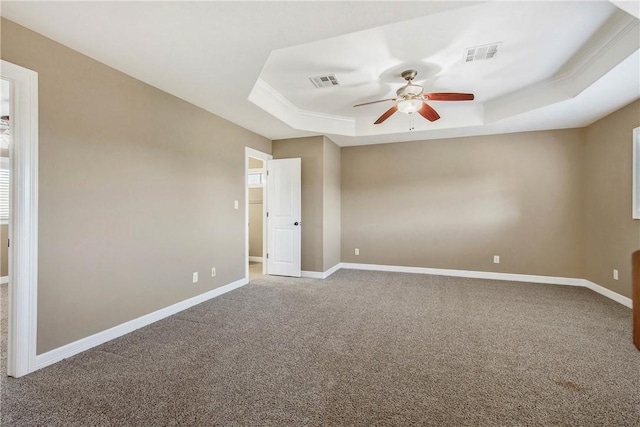 spare room featuring a tray ceiling, baseboards, visible vents, and ceiling fan