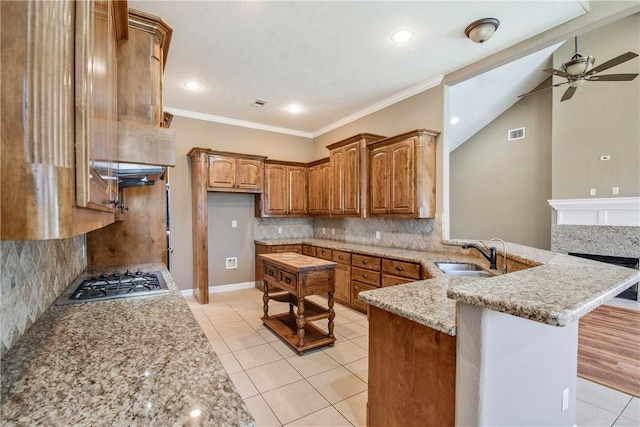 kitchen featuring light tile patterned floors, a ceiling fan, stainless steel gas cooktop, a peninsula, and brown cabinets