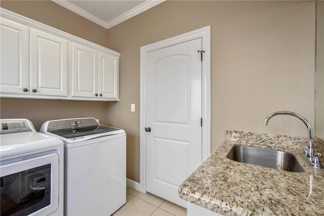 laundry area featuring light tile patterned floors, cabinet space, a sink, ornamental molding, and washer and clothes dryer