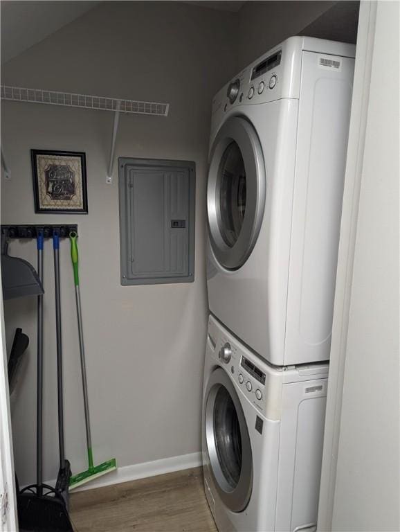 clothes washing area with stacked washer and dryer, electric panel, and light hardwood / wood-style floors