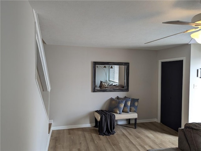 living area with ceiling fan, light hardwood / wood-style floors, and a textured ceiling