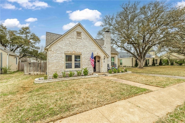 view of front of house with fence, a shingled roof, a chimney, a front lawn, and brick siding