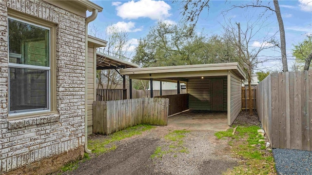 exterior space featuring a carport, aphalt driveway, and fence