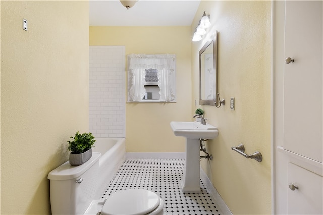 bathroom featuring toilet, baseboards, and a sink