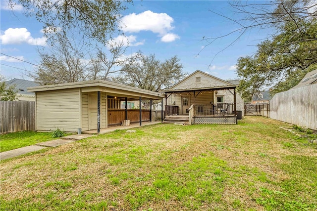 rear view of house featuring a deck, an outbuilding, a yard, and a fenced backyard