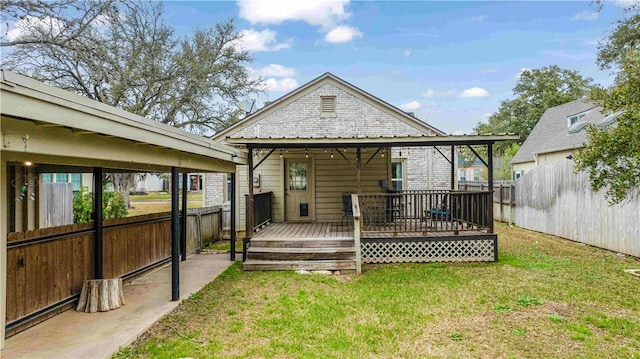 rear view of house with a deck, fence, and a lawn