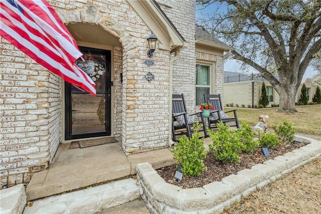 entrance to property with stone siding, brick siding, and roof with shingles