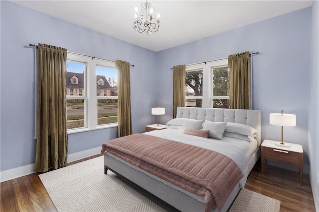 bedroom with multiple windows, wood finished floors, baseboards, and a chandelier