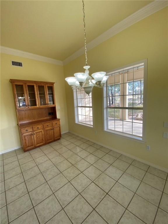 unfurnished dining area featuring crown molding, light tile patterned floors, and a notable chandelier