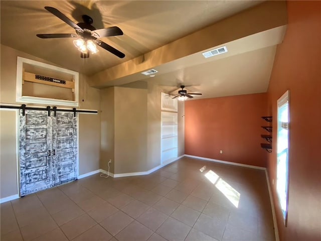 tiled empty room with ceiling fan and built in shelves