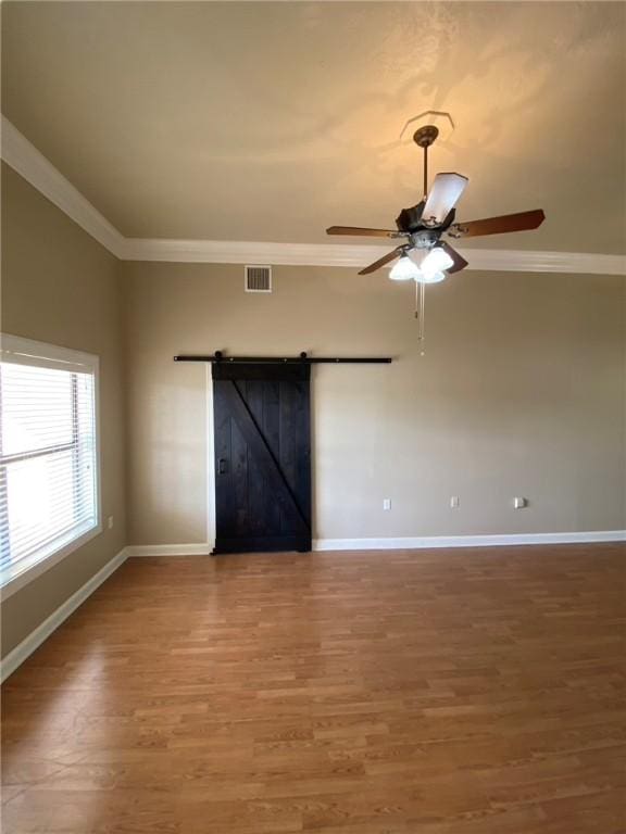 unfurnished room with hardwood / wood-style floors, a barn door, ceiling fan, and ornamental molding