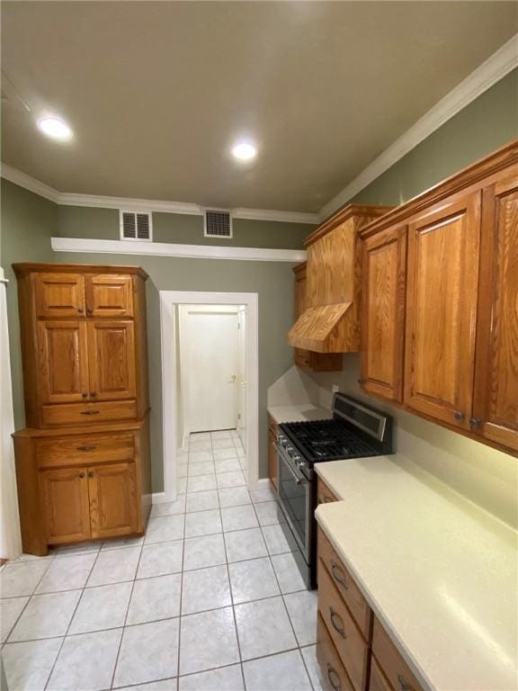 kitchen featuring light tile patterned flooring, crown molding, extractor fan, and stainless steel gas range