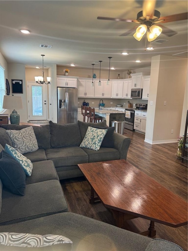 living area with visible vents, baseboards, ceiling fan with notable chandelier, dark wood-style floors, and recessed lighting