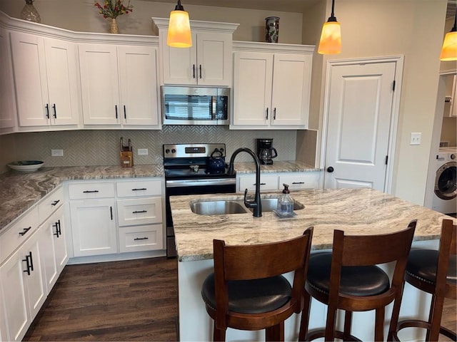 kitchen featuring white cabinets, appliances with stainless steel finishes, washer / dryer, and dark wood-type flooring