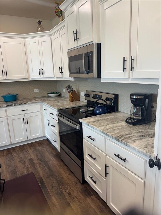 kitchen featuring appliances with stainless steel finishes, tasteful backsplash, light stone counters, white cabinets, and dark wood-type flooring