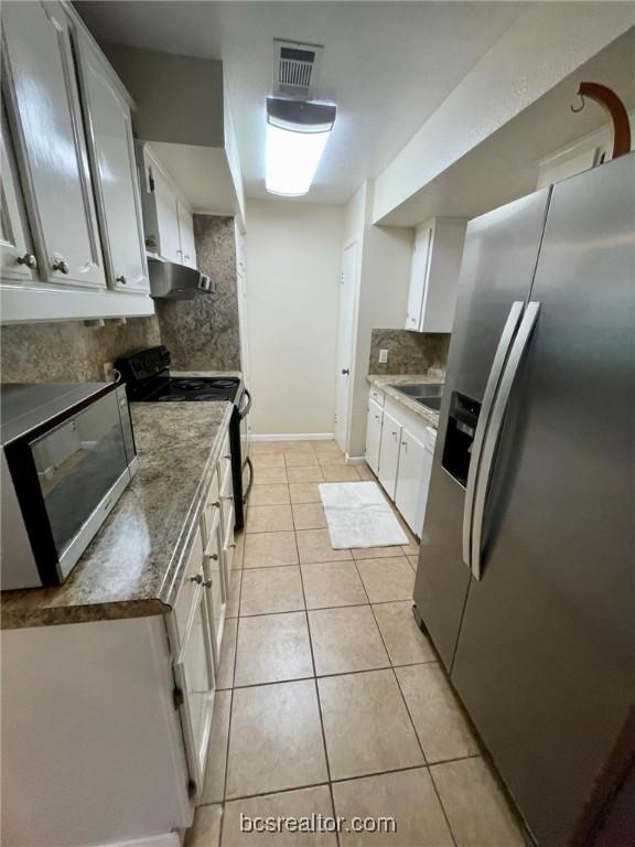 kitchen with decorative backsplash, white cabinetry, light tile patterned flooring, and appliances with stainless steel finishes