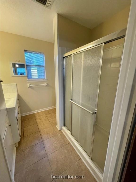 bathroom with tile patterned floors, vanity, and a shower with shower door