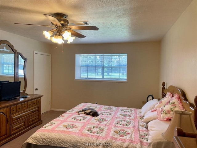 bedroom with dark colored carpet, a textured ceiling, and ceiling fan