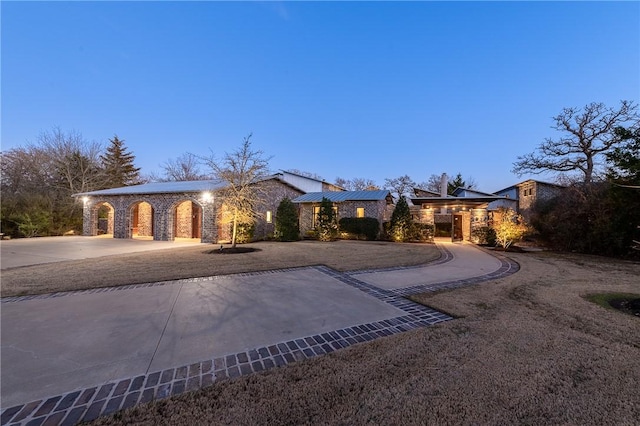 view of front of house with stone siding, roof mounted solar panels, and curved driveway