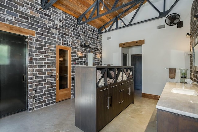 kitchen featuring visible vents, high vaulted ceiling, a sink, wood ceiling, and concrete flooring