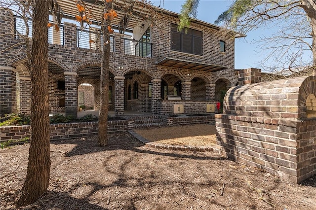 view of front of house with brick siding and a patio area