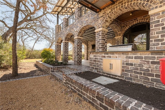 property entrance with brick siding, stone siding, an outdoor kitchen, and a patio