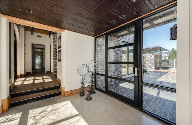 interior space with concrete floors, baseboards, and an ornate ceiling