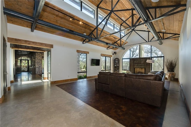 living area with a healthy amount of sunlight, a fireplace, high vaulted ceiling, and concrete floors