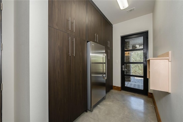 kitchen featuring visible vents, concrete floors, baseboards, dark brown cabinets, and stainless steel fridge