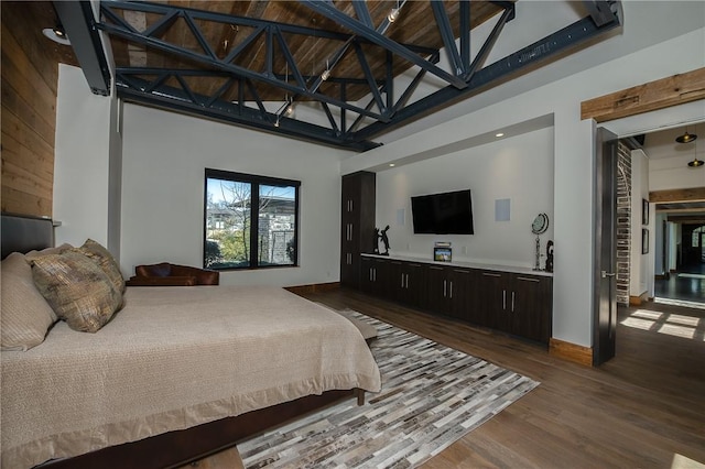 bedroom with dark wood finished floors, high vaulted ceiling, and baseboards